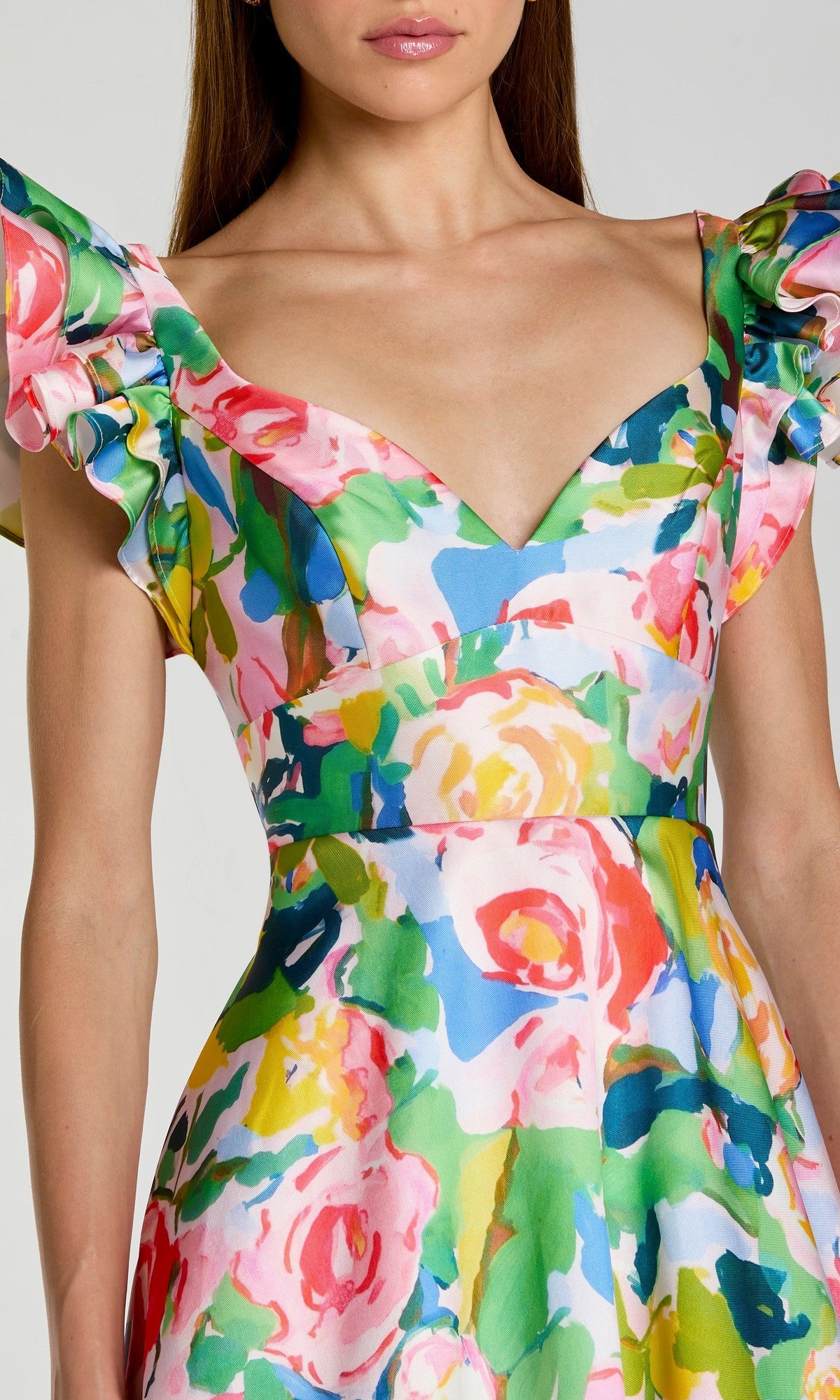 A woman wearing the Long Formal Dress: Mac Duggal 56341, a colorful floral Mikado gown with ruffled sleeves and a deep V-neckline, shown from shoulders to waist.